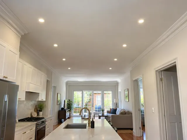Open-plan kitchen and living room with ceiling downlights in a painted home interior in North Sydney