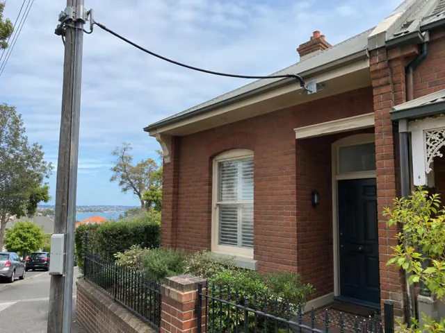 Brick house exterior with new overhead service cable and point-of-attachment bracket on the eaves in Neutral Bay